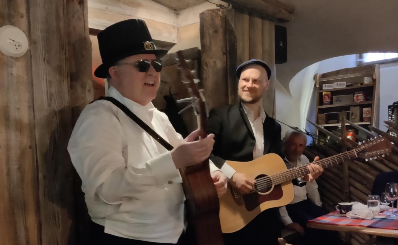 Russ palmer har doktorhatt på huvudet och en gitarr i handen