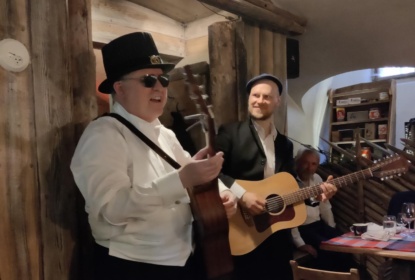Russ palmer har doktorhatt på huvudet och en gitarr i handen