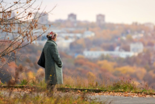 Old widow walking in autumn city park