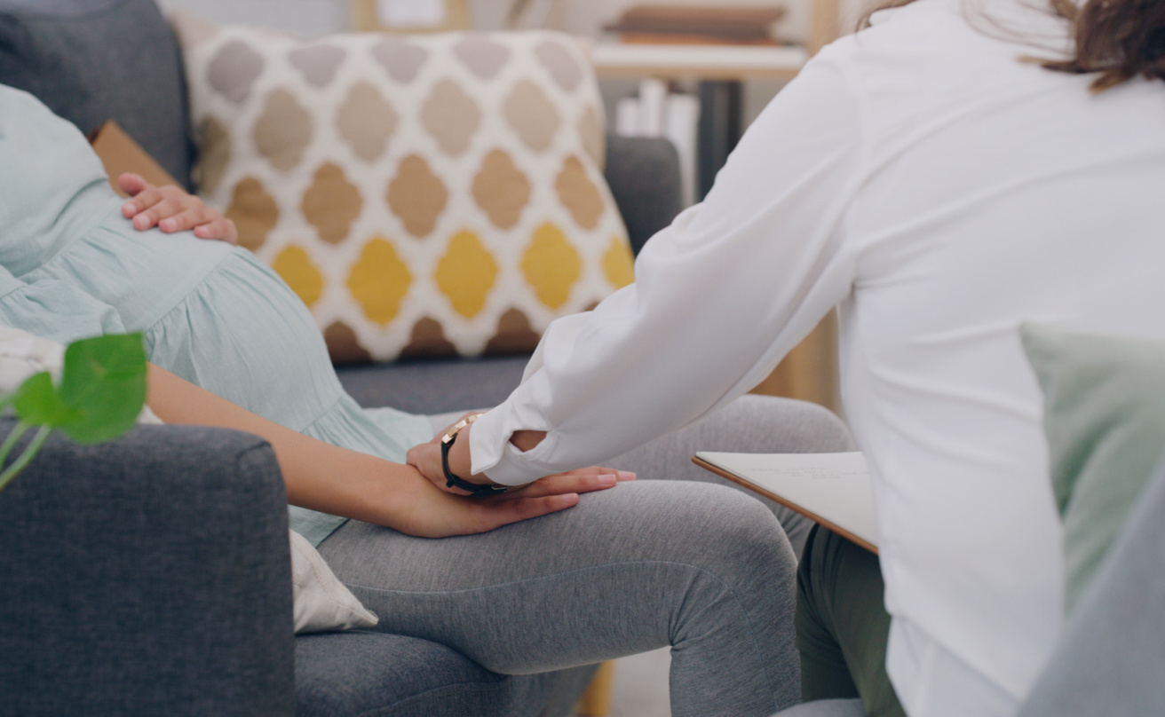Pregnant woman holding hand with nurse