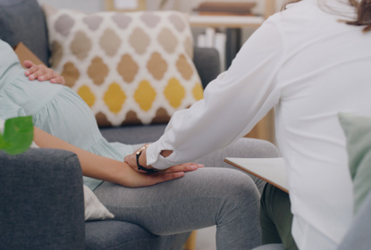 Pregnant woman holding hand with nurse
