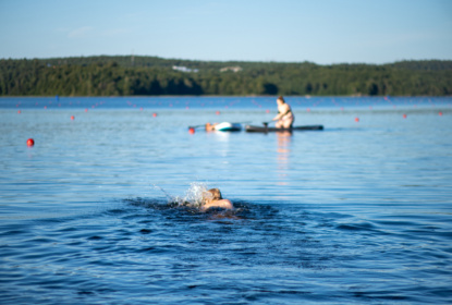 Child swimming in a lake in rural Scandinavia on a sunny summer day