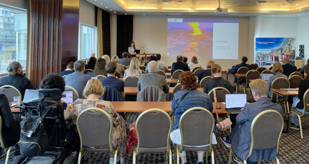 Conference room full of people, looking at powerpoint picture of volcano eruption