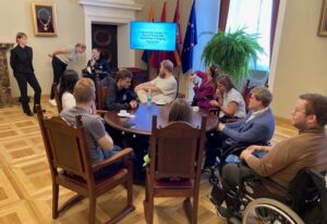 Young people gathered at Youth summit around a table to discuss. Some with visible disabilities. 