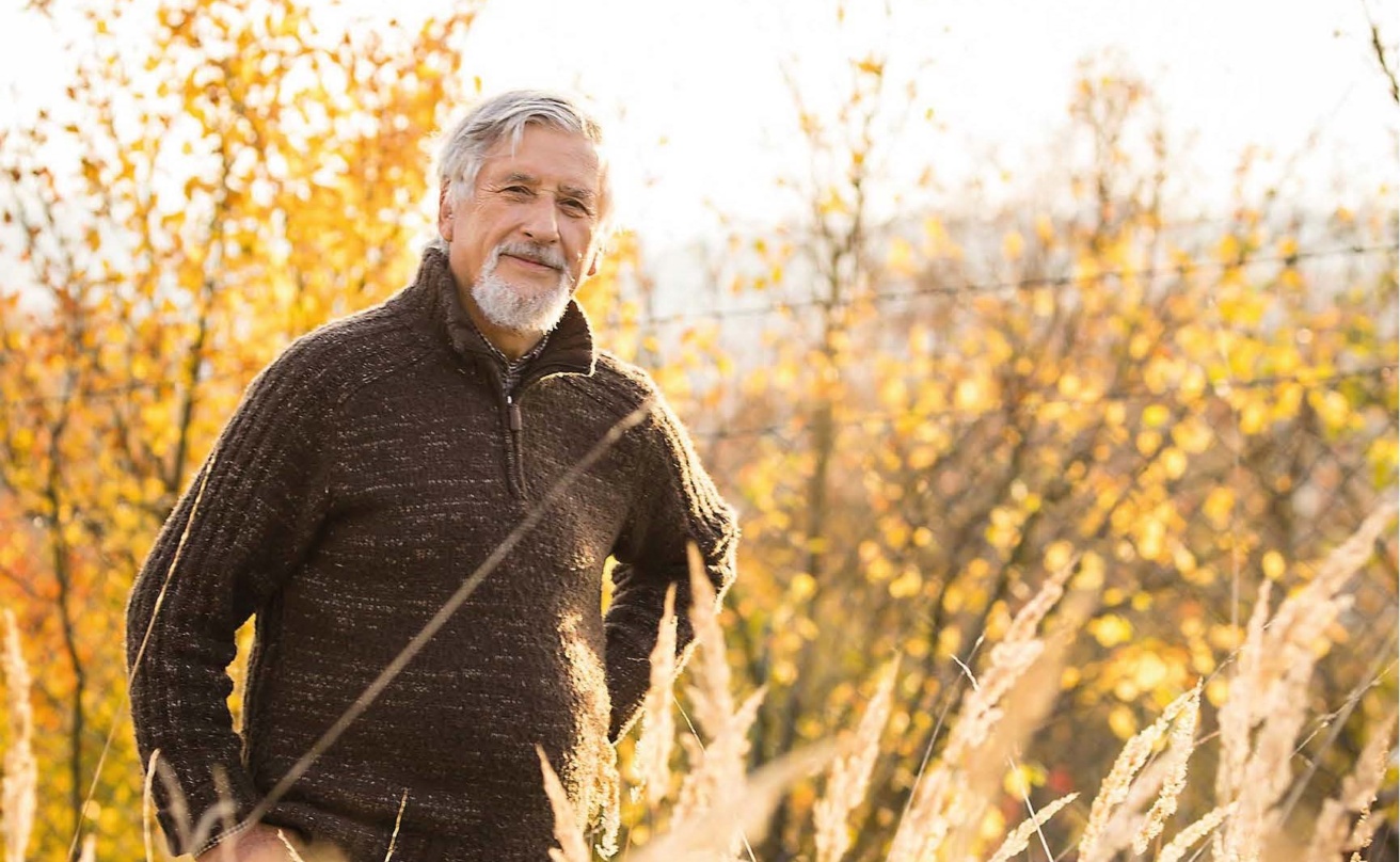 A man standing among yellow autumn leaves.