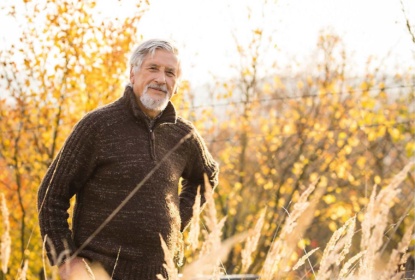 A man standing among yellow autumn leaves.