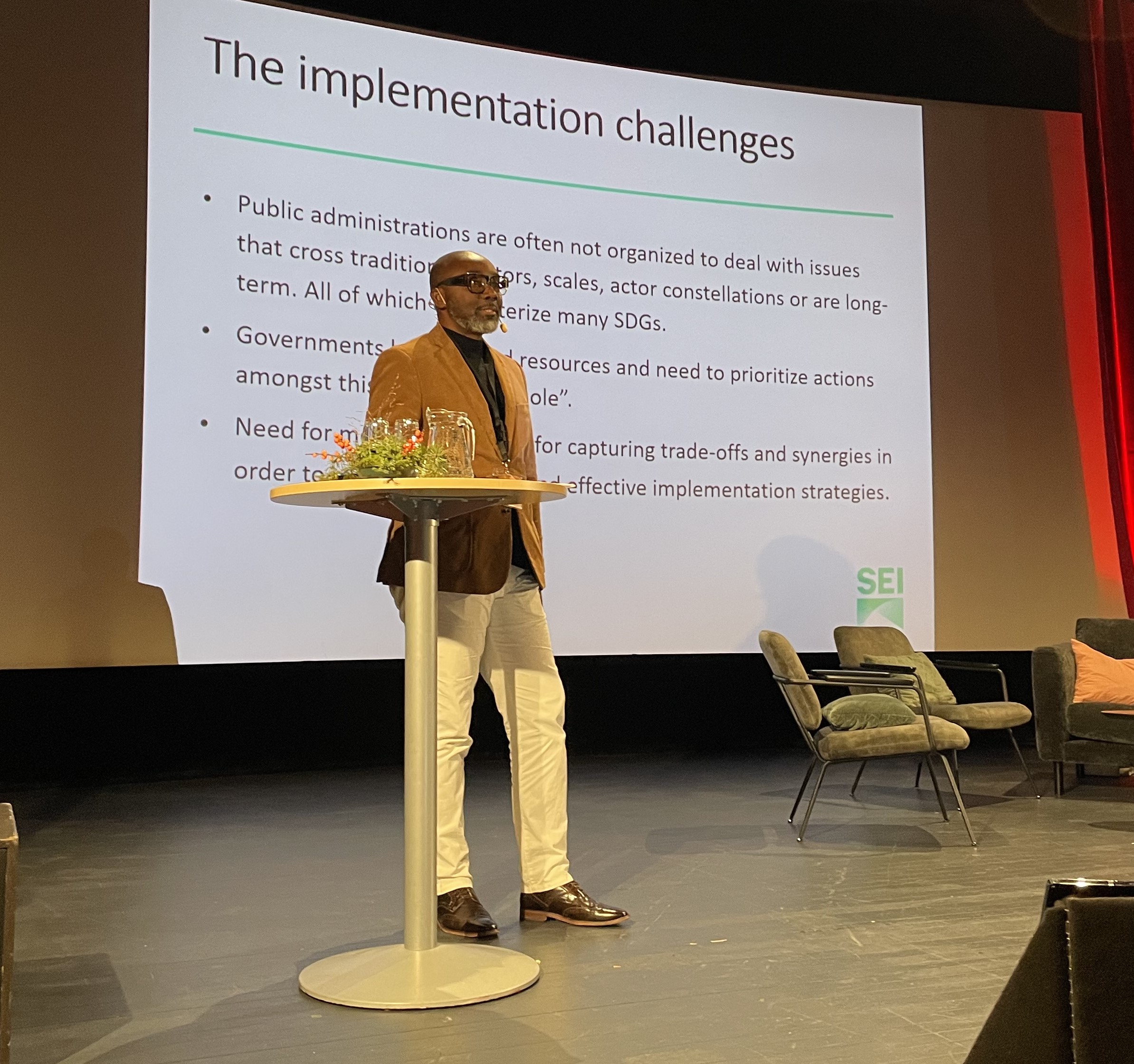 Nelson Ekane giving a speech on a stage 