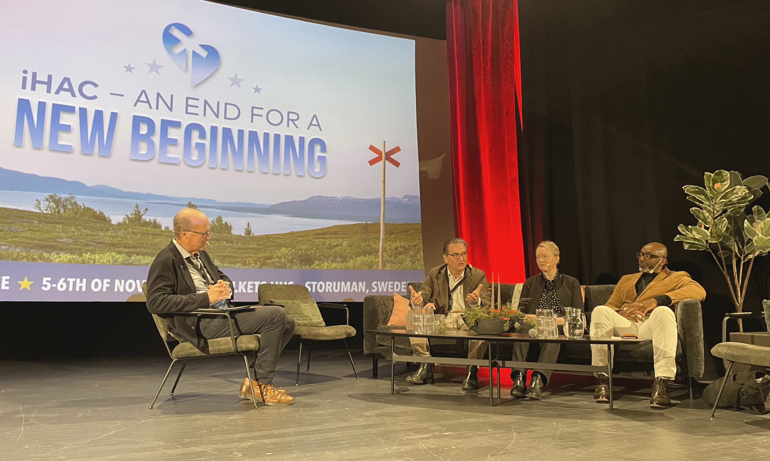 Four people having a panel discussion on a big stage.