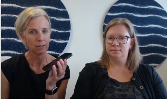 two women talking, one holding a phone to show digital inclusion