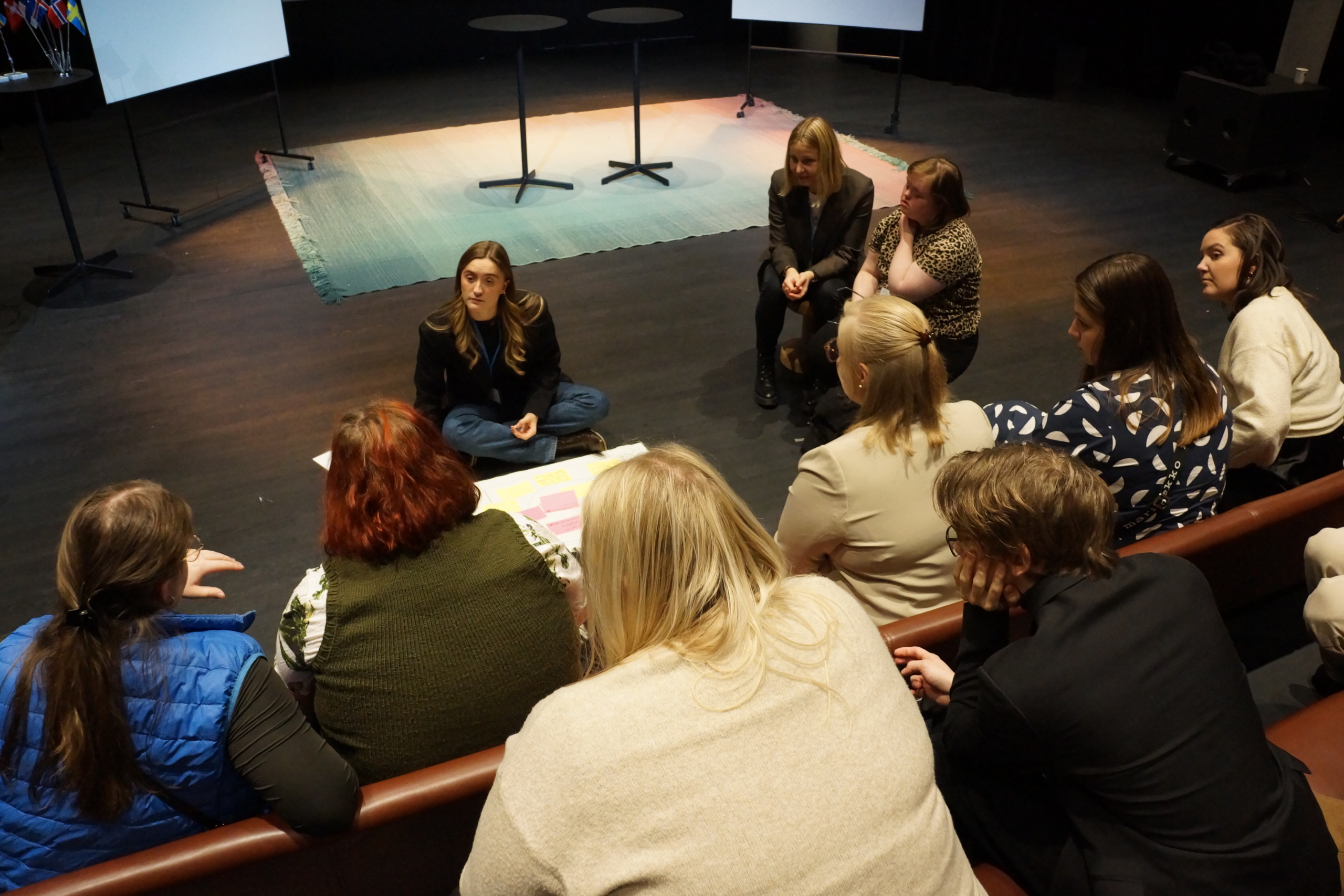 Ungdomar sitter i en föreläsningssal och diskuterar.