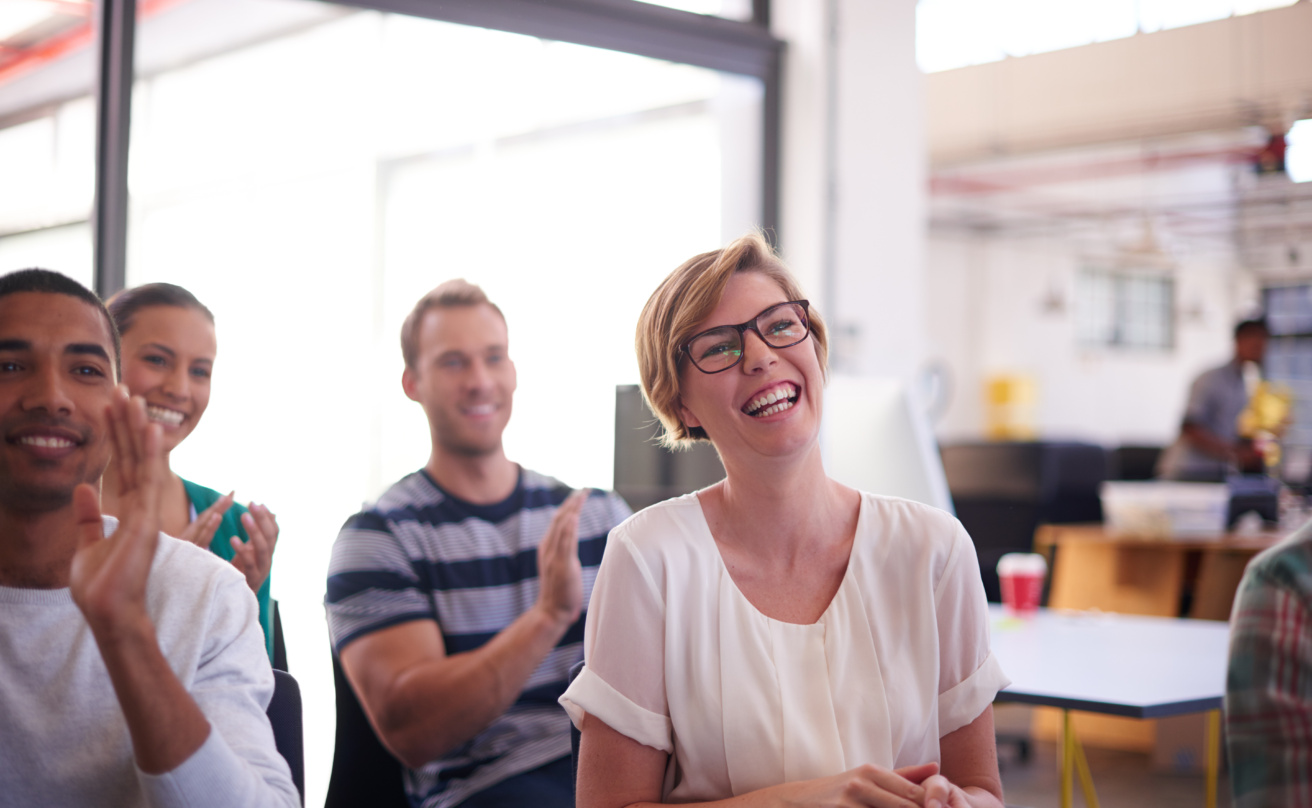 Two men and two women sitting at a seminar, applauding and looking happy