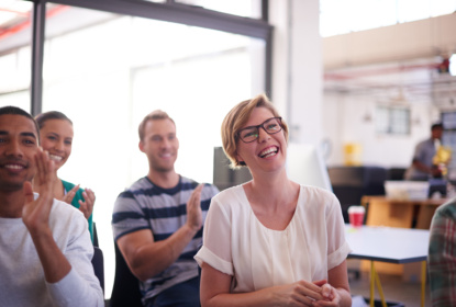 Two men and two women sitting at a seminar, applauding and looking happy