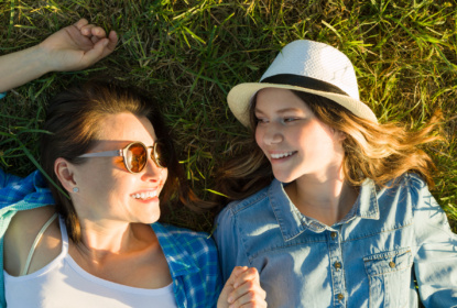 mom and teenage daughter lying in the grass
