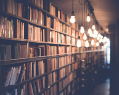 Bokhyllor fyllda med böcker i ett bibliotek, med hängande lampor längs gången.
