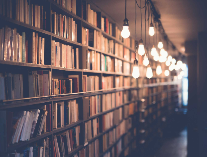 Bokhyllor fyllda med böcker i ett bibliotek, med hängande lampor längs gången.