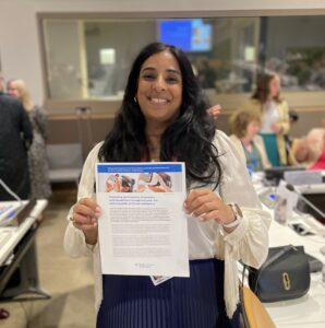 Minister Lubna Jaffery holding a document and smiling