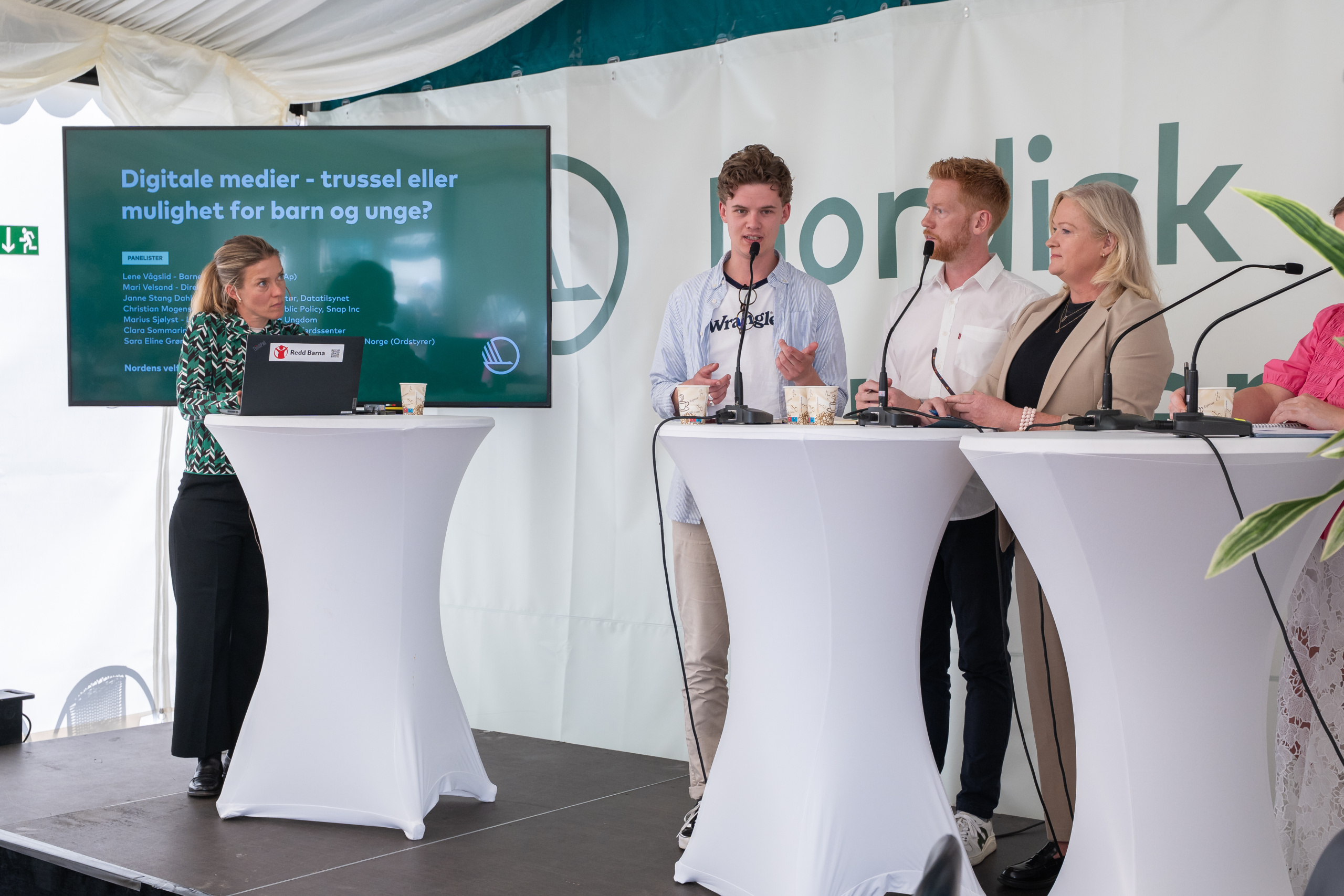 Moderator och tre paneldeltagare i diskussion på scen