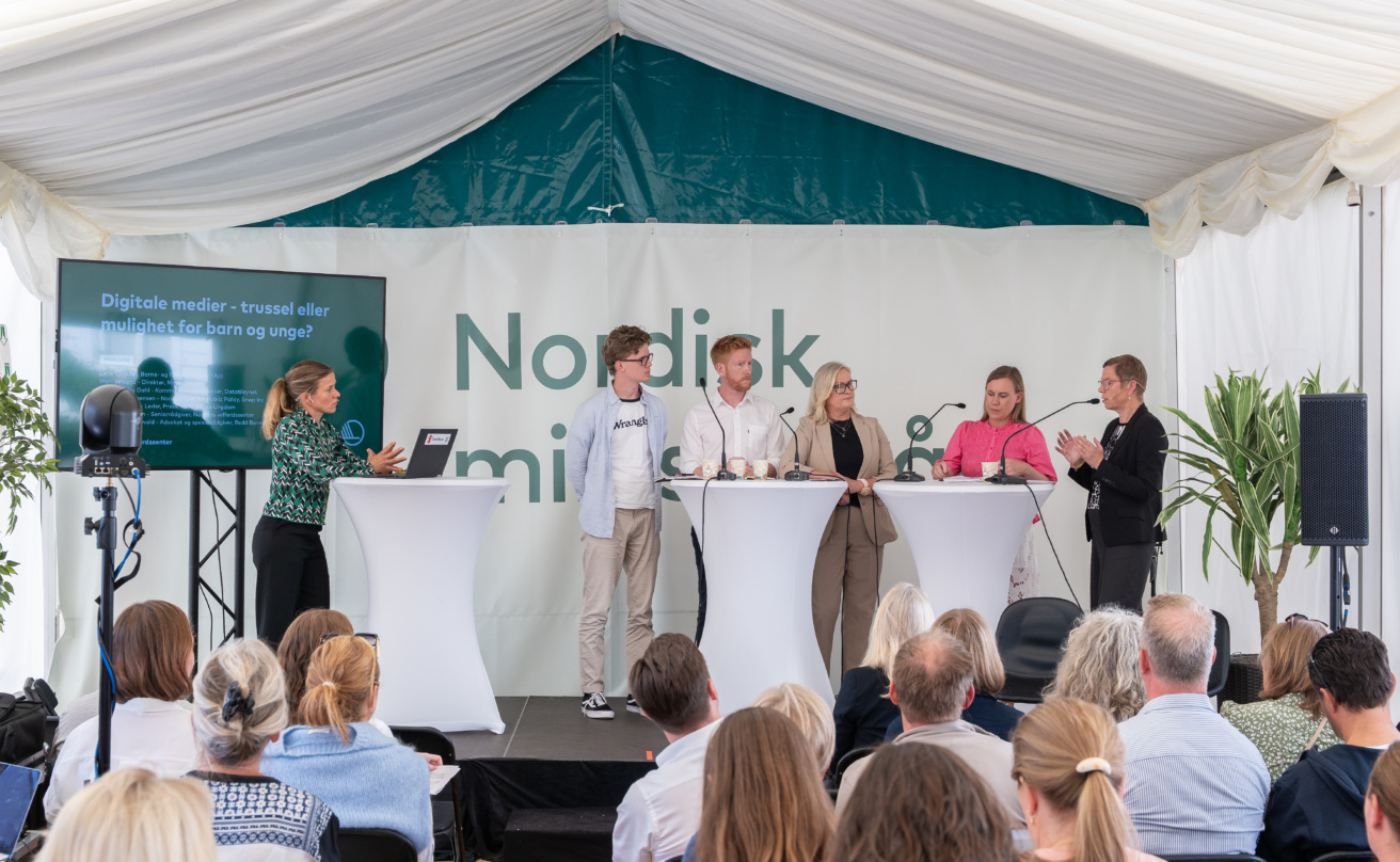 Paneldiskussion på scen i Nordens Telt, moderator och fem deltagare.