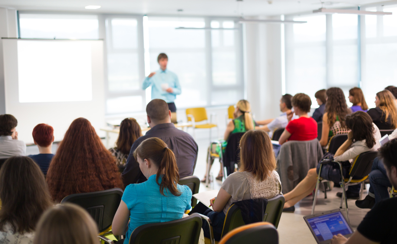 man speaking in fron of audience at event