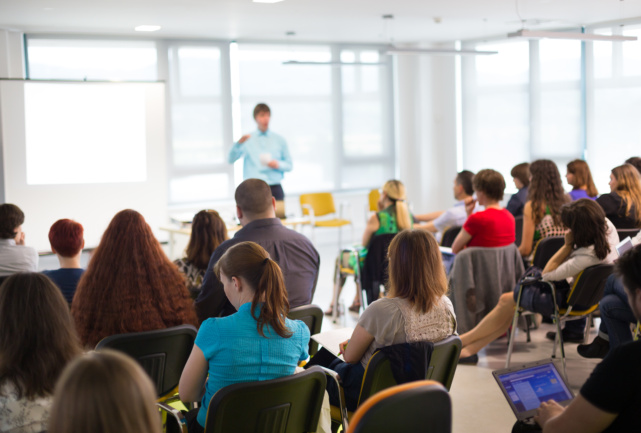 man speaking in fron of audience at event