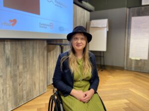 Porträtt av Hanna Öfors, som har grön klänning och svart hatt