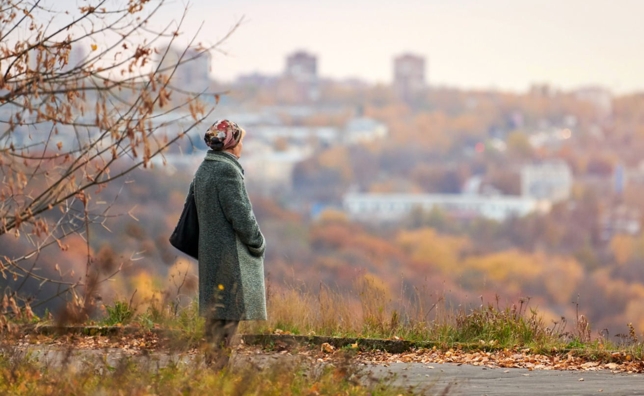 Old widow walking in autumn city park