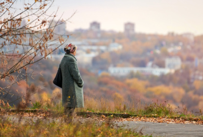 Old widow walking in autumn city park