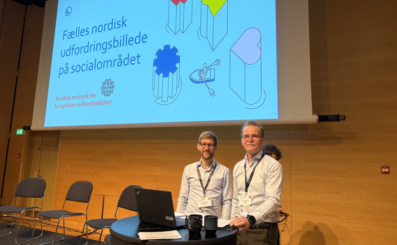 Två män står på scen i konferenslokal