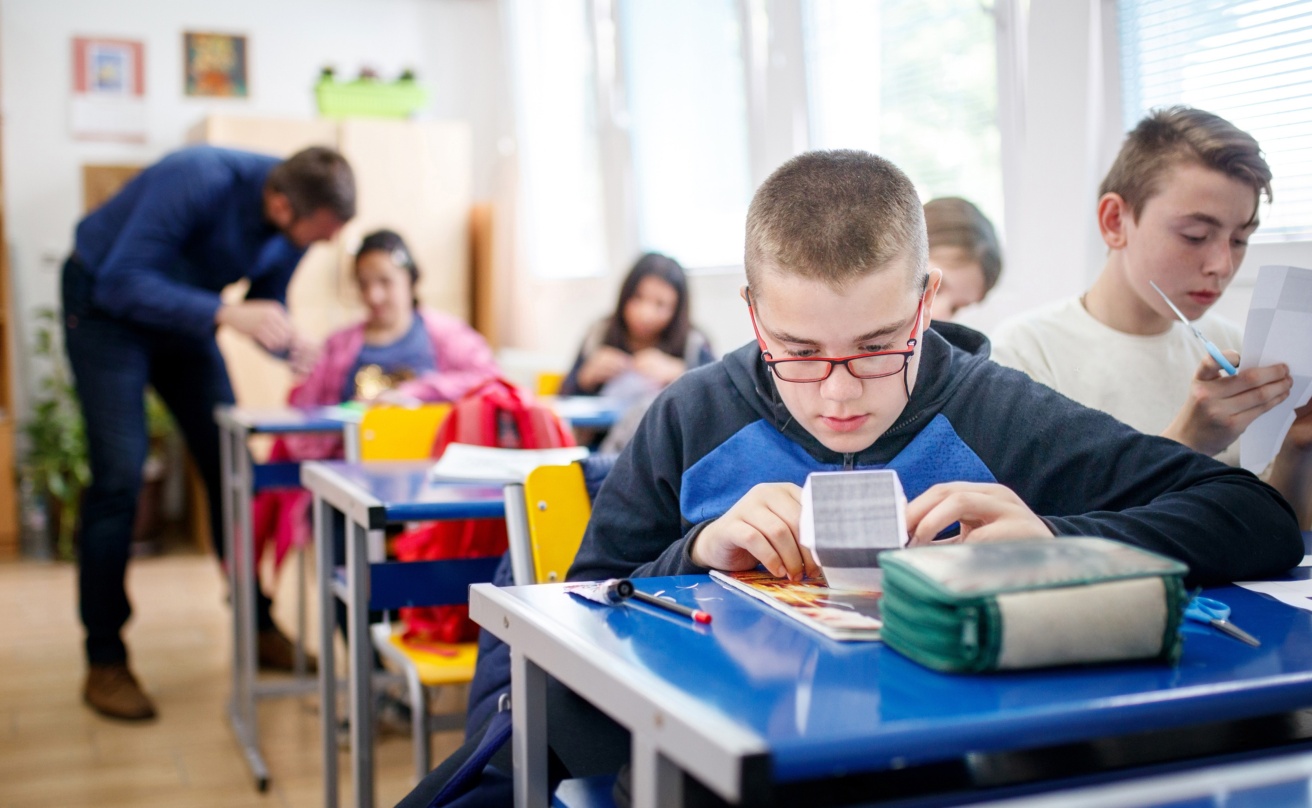 pojke i klassrum jobbar med anpassat lärmaterial