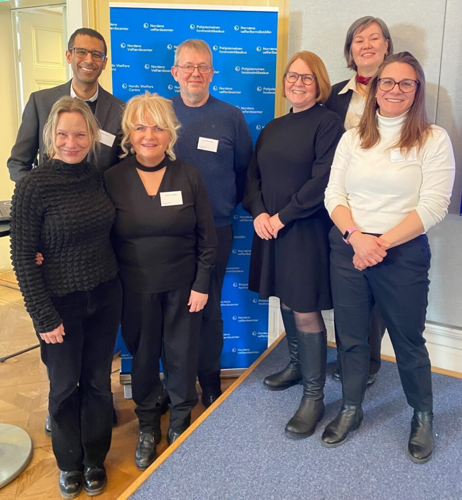 Participants in panel discussion posing on and beside stage.