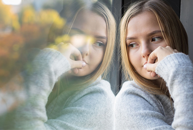 Ung kvinna sitter och tittar ut genom ett fönster