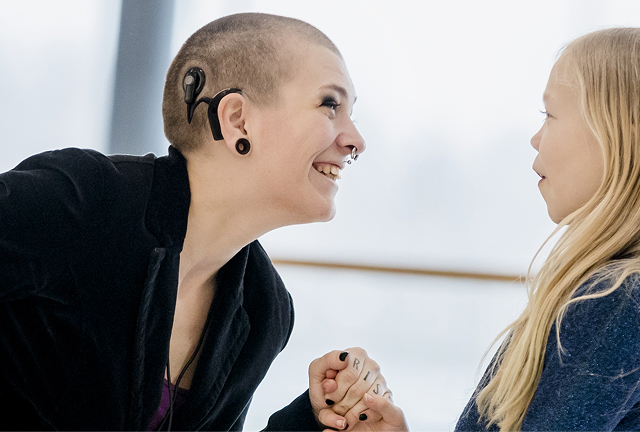 Leende kvinna med hörapparat möter en glad flicka