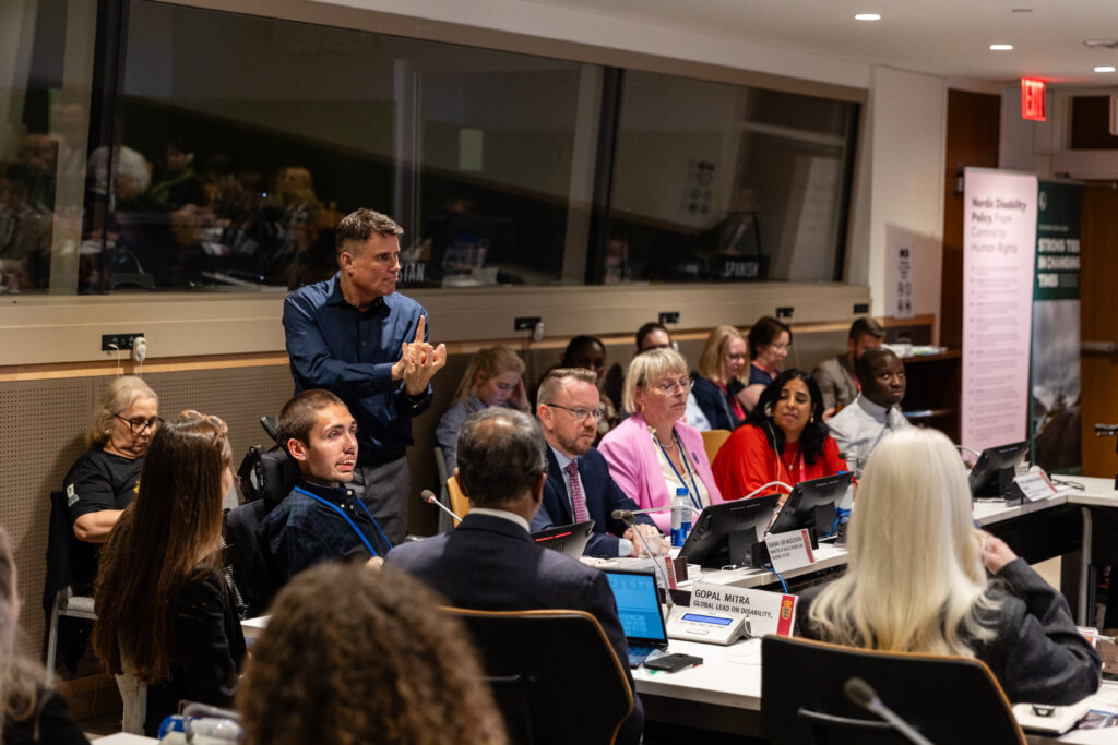 Conference room in the UN: Moderator william korte is speaking, three ministers are listening. Audience and panel members in the background. A sign language interpreter stands behind William.