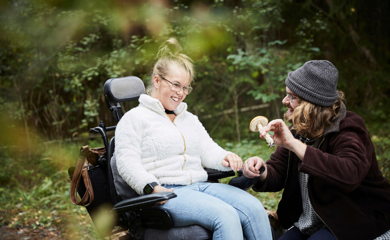 young woman in wheelchair, looking at a mushroom together with a man