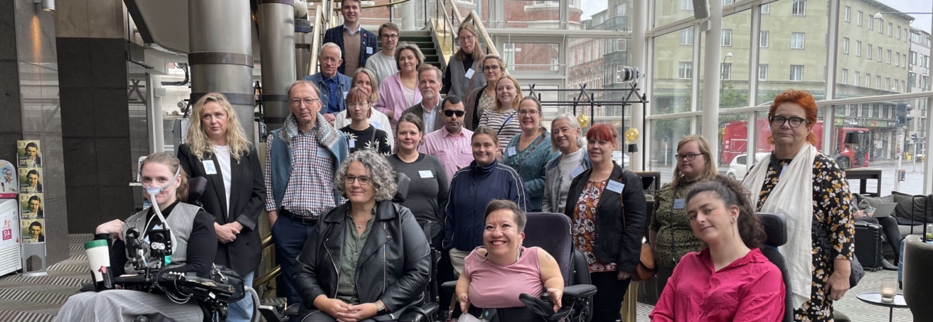 Gruppbild av medlemmarna i Rådet för nordiskt samarbete om funktionshinder tillsammans med deltagarna i Nordic Youth Disability Summit i Malmö 2024. 24 står eller sitter i rullstol i en inglasad hotellobby.