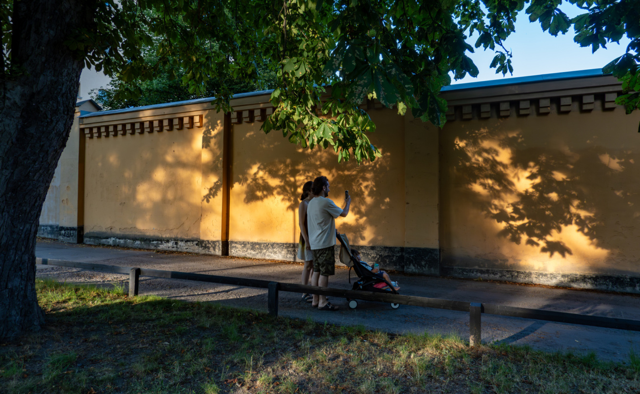 A young couple walk in the Langholmen park at sunset with a child.
