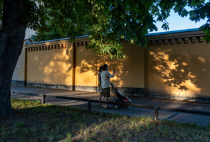 A young couple walk in the Langholmen park at sunset with a child.