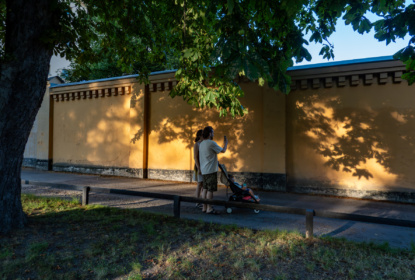 A young couple walk in the Langholmen park at sunset with a child.