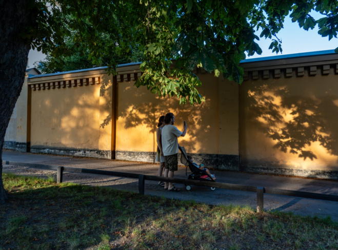 A young couple walk in the Langholmen park at sunset with a child.