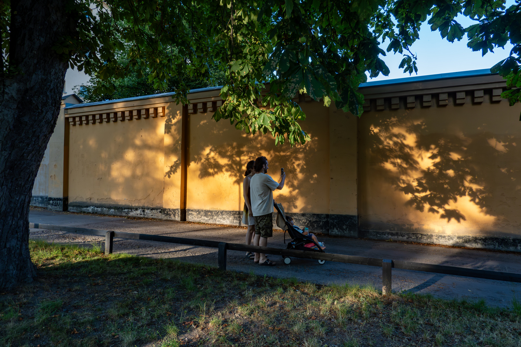 A young couple walk in the Langholmen park at sunset with a child.