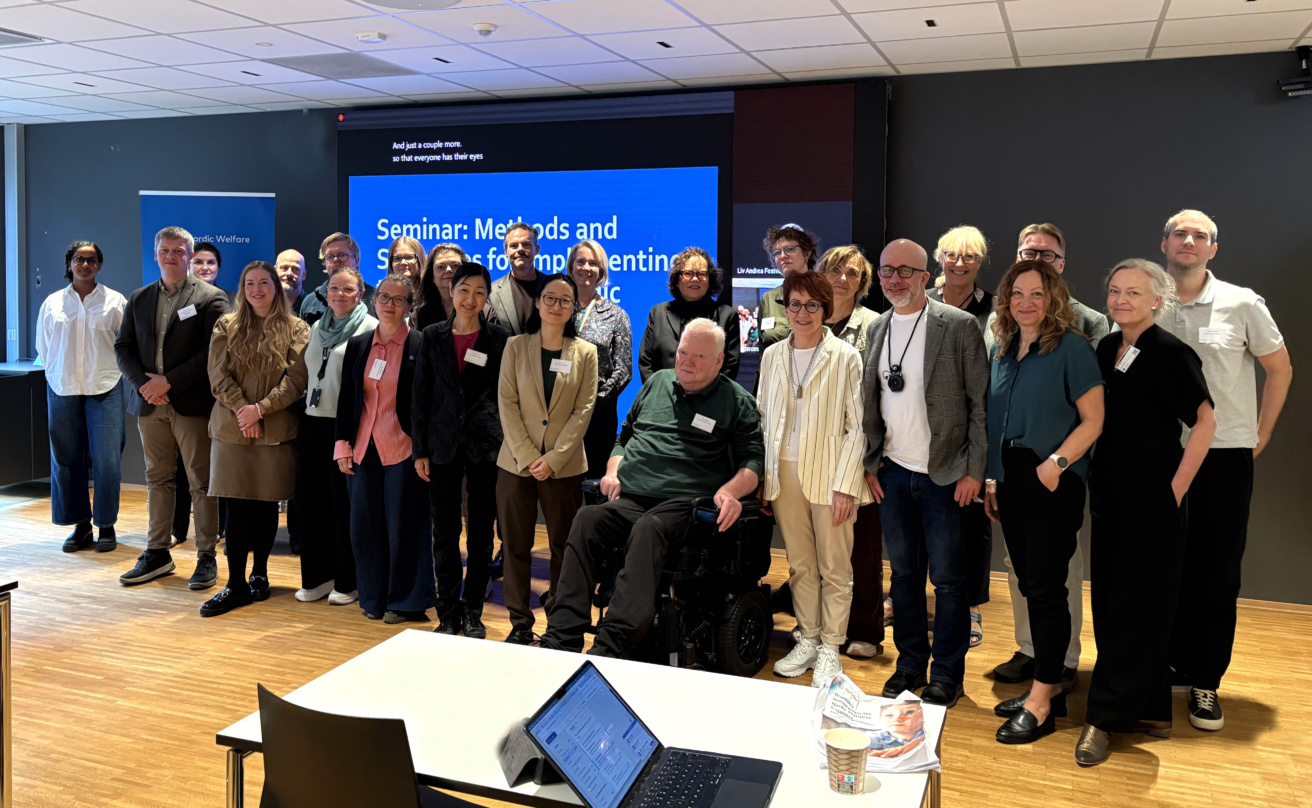 Group picture with 25 people standing in a conference room