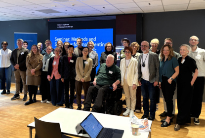 Group picture with 25 people standing in a conference room