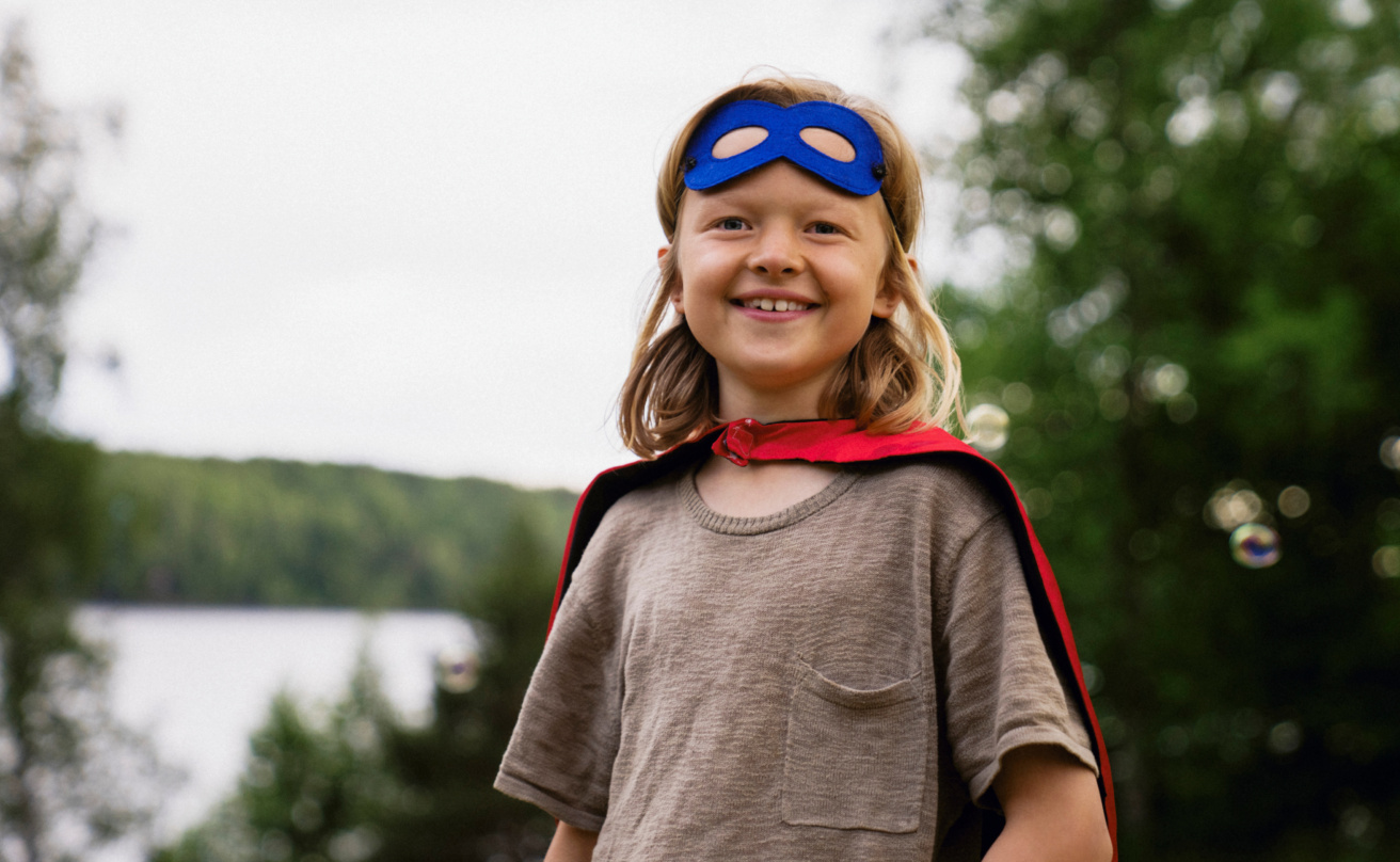 smiling-long-haired-boy-wearing-superhero-custome-at-summer-camp