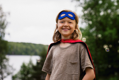 smiling-long-haired-boy-wearing-superhero-custome-at-summer-camp