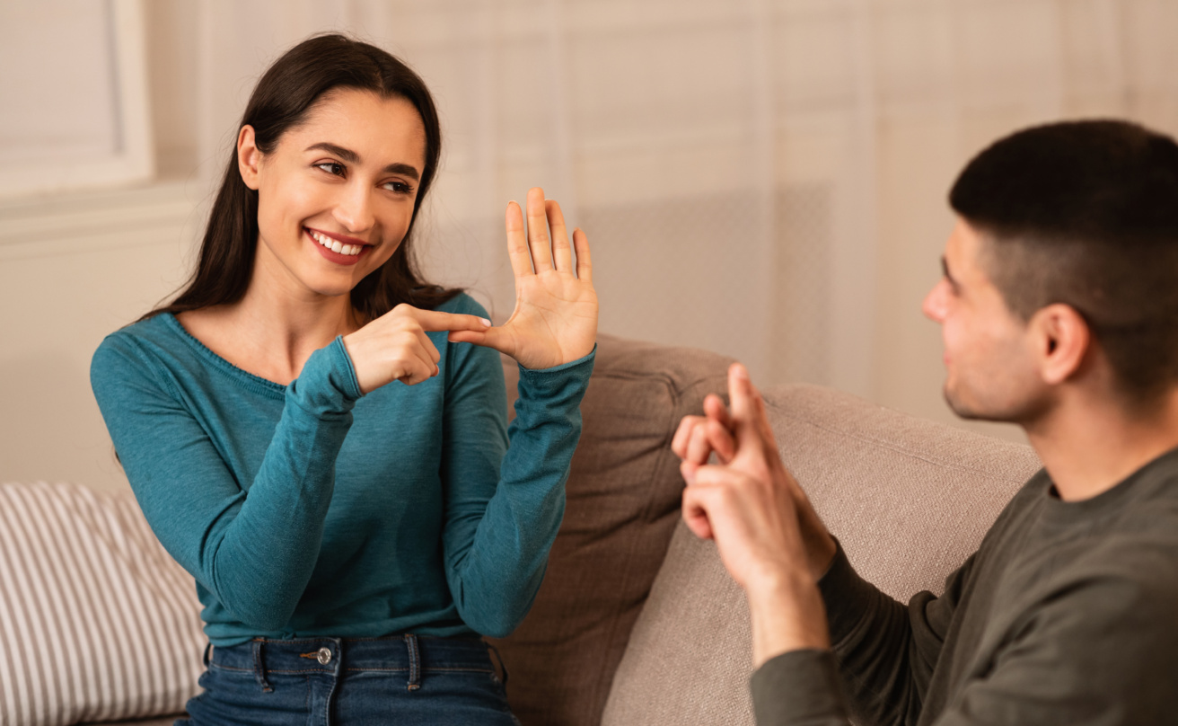 Couple Sitting On Sofa Communicating With Sign Language