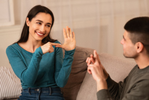 Couple Sitting On Sofa Communicating With Sign Language
