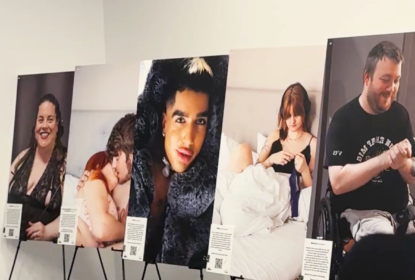 Five large portrait photographs of people with deafblindness in different everyday situations, displayed on black easels at an exhibition. Each photograph is accompanied by an information card with text and a QR code.